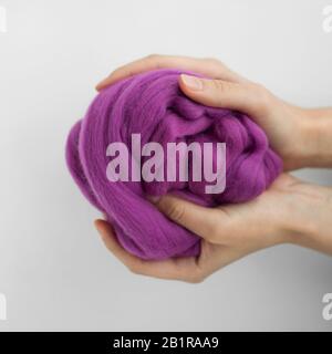 Close-up of violet merino wool ball in hands. Stock Photo