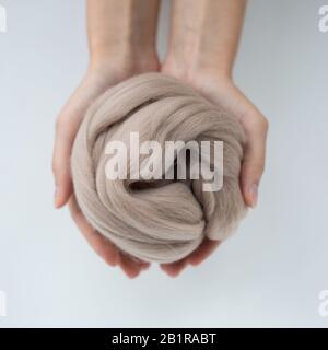 Close-up of brown merino wool ball in hands. Stock Photo