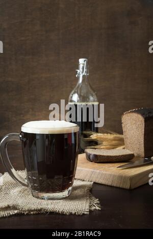 Russian traditional drink fermented kvass from rye bread in special half-liter mug on dark background. Vertical format. Stock Photo