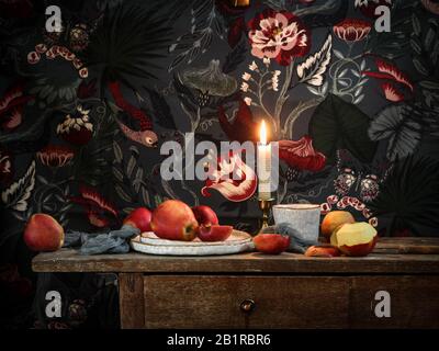 Dark mood still life with apples on a rustic table on a colorful wallpaper background Stock Photo