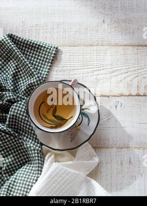 A lovely cup of tea with a floral decor and two napkins on a white wooden table with a large space for your product or text Stock Photo