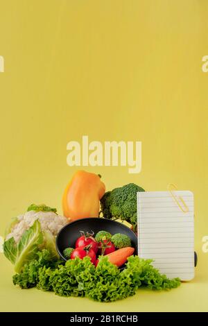 Vegetables and notebook with copy space on yellow background. Bio Healthy food, Organic vegetables on yellow background Stock Photo