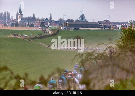 Viesly, France - April 14, 2019: The peloton riding on the cobblestone road from Briastre to Viesly during Paris Roubaix 2019. Stock Photo