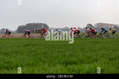 Viesly, France - April 14, 2019: The peloton riding on the dusty cobblestone road from Cysoing to Bourghelles during Paris Roubaix 2019. Stock Photo