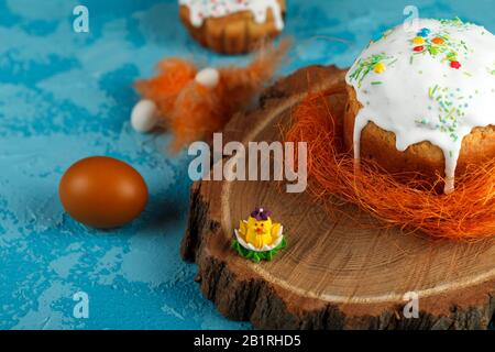 Fresh Easter cake, baked at home and decorated with sweet icing. Colored boiled eggs lie on the table as an element of the Easter holiday. Artificial Stock Photo