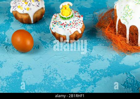 Fresh Easter cake, baked at home and decorated with sweet icing. Colored boiled eggs lie on the table as an element of the Easter holiday. Artificial Stock Photo