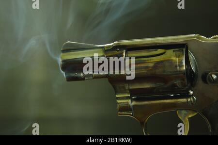 revolver gun muzzle with smoke floating in the air after shoot on black background Stock Photo