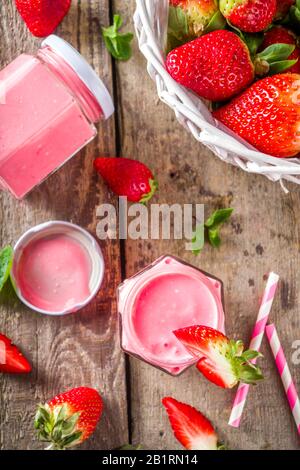 Strawberry milkshake in bottles, with fresh strawberries and mint on sunlight summer wooden and glass background, copy space Stock Photo