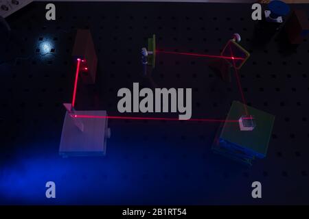 Experiment in optic lab with laser device. Red laser on optical table in physics laboratory Stock Photo