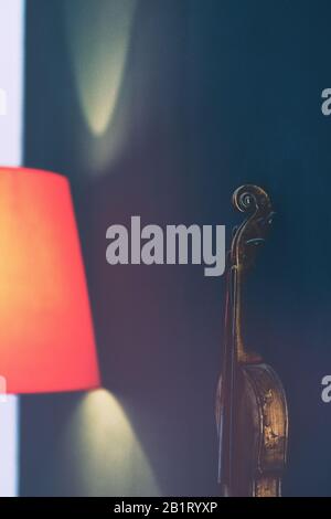 Violin on the wall by the red lamp Stock Photo