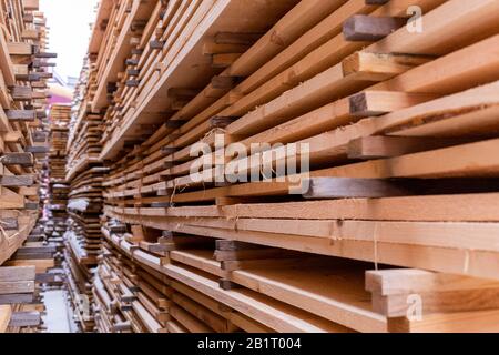 Large stacks of wooden planks background with selective focus and linear perspective. Winter woodwork industrial storage. Stock Photo