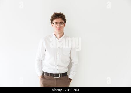 Handsome confident young curly haired businessman wearing white shirt standing infront of isolated background, posing Stock Photo