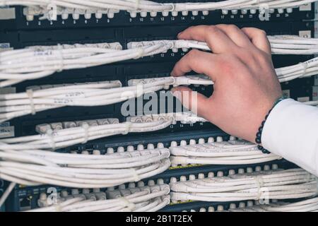 man working in network server room with fiber optic hub for digital communications and internet Stock Photo