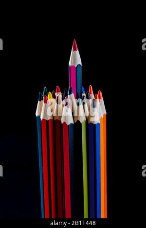Group of pencils with one sticking out from the group, odd one out. Colourful pencils. Stock Photo