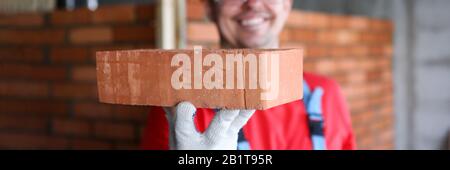 Smiling male builder showing fine quality brick material in camera Stock Photo
