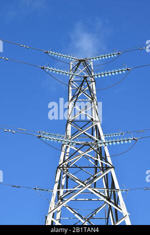 Electricity pylon against blue sky background with insulating cables, glass cups and bypass lines Stock Photo