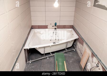 Bathroom interior with rectangular ceramic tiles on walls, electronic level in bath, repair, reconstruction, even rows of new tile, top view Stock Photo