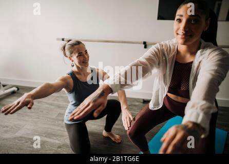 Female personal trainer coaches her female student how to squat Stock Photo