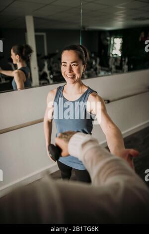 smiling female personal trainer coaches a person lifting weights Stock Photo