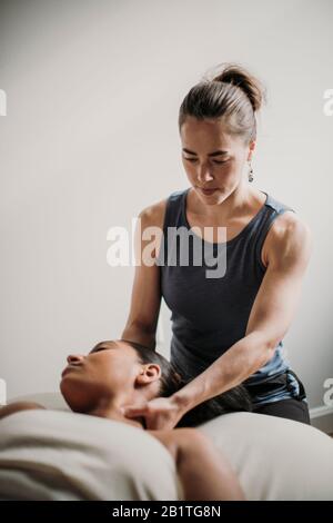 female massage therapist treats her african american patient Stock Photo