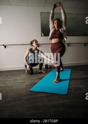 female personal trainer coaches female client on lunge technique Stock Photo