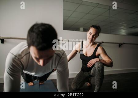 female personal trainer coaches male client doing push ups Stock Photo