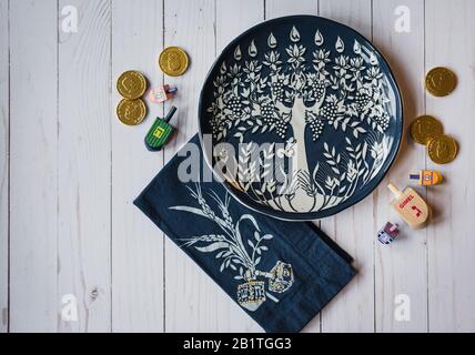 Decorative Hanukkah plate, dreidels and chocolate coins on white wood. Stock Photo