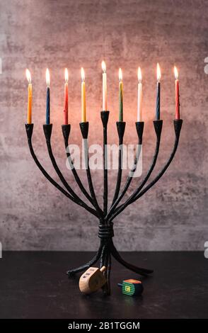 Menorah with lit candles and dreidels on a table for Hanukkah. Stock Photo