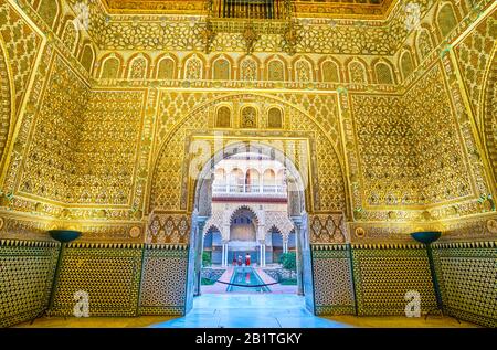 SEVILLE, SPAIN - OCTOBER 1, 2019: The scenic ornate wall of the Ambassadors Hall with arched entrance to the Courtyard of the Maidens with small pool, Stock Photo