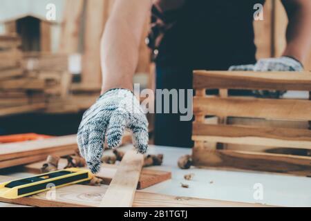 DIY woodworking and furniture making and craftsmanship and handwork concept. Carpenter working on woodworking machines in carpentry shop. Young man wo Stock Photo