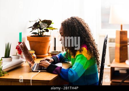 Side view of girl using laptop while sitting at table in living room Stock Photo