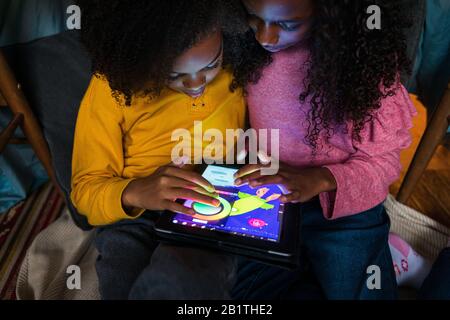 Siblings playing video game on digital tablet at home Stock Photo