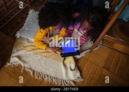 High angle view of sisters using digital tablet while lying at home Stock Photo
