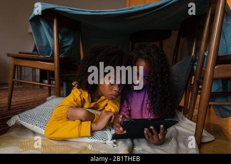 Sisters using digital tablet while lying at home Stock Photo