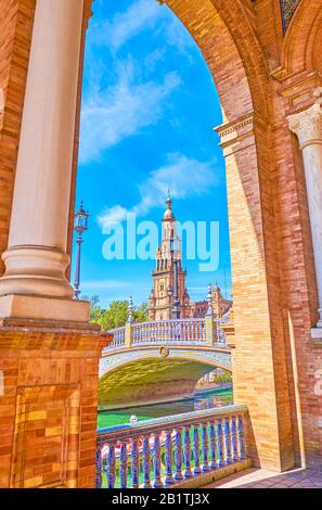The view on the tower through the arches of brick gallery's arcades of Plaza de Espana in Seville, Spain Stock Photo