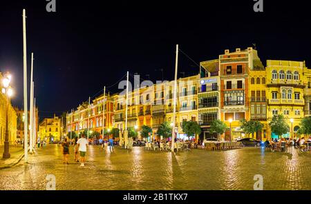 SEVILLE, SPAIN - OCTOBER 1, 2019: Panoramic view on the bright illuminated historical mansions with outdoor cafes on San Francisco square, on October Stock Photo