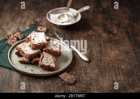 Slices Homemade brownie cakes with dark chocolate sprinkled with icing sugar on a dark background. Place for text Stock Photo