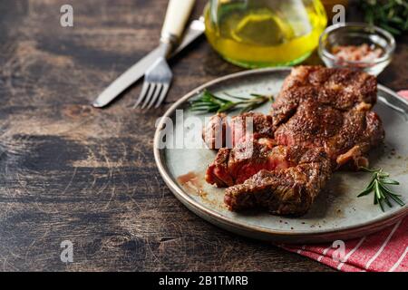 Fresh grilled beef steak Prime Black Angus Chuck roll steak sliced into pieces on dish on wooden table. Place for text Stock Photo