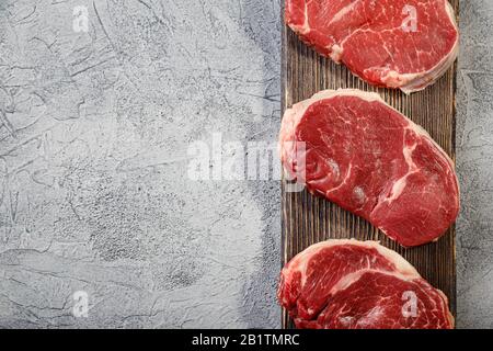 Three pieces of traditional thin steak cut from the tenderloin on wooden cutting board. Steak has good marbling, beautiful even shape and delicate mea Stock Photo