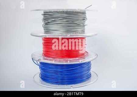 Coils of plastic for 3D printing. Red, silver and blue plastic filament, ABS/PLA coil for 3d printer on white background, isolated Stock Photo