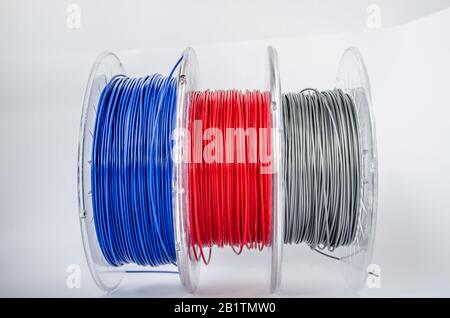 Plastic for 3D printing. Red, silver and blue plastic filament, ABS/PLA coil for 3d printer on white background, isolated Stock Photo