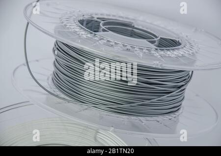 Close up view of plastic for 3D printing. Silver plastic filament, gray ABS/PLA coil for 3d printer isolated on white background. Stock Photo