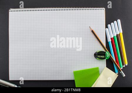 Blank notepad with copy space and creative toolkit. School supplies and blank notebook on black background, space for text, top view. Stickers, felt Stock Photo