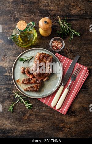 Fresh grilled beef steak Prime Black Angus Chuck roll steak sliced into pieces on dish on wooden table. Top view Stock Photo