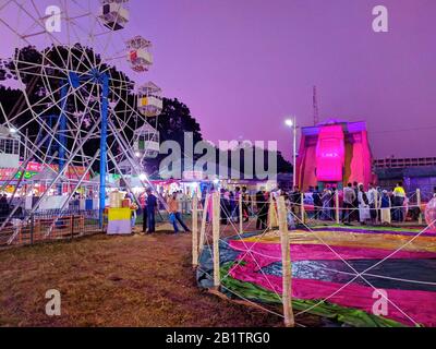 Night shot of a ferris wheel in exhibition fair.people and fairground rides at the biggest fair. Ferris Wheel at local County Fair.Colorful Trade fair Stock Photo