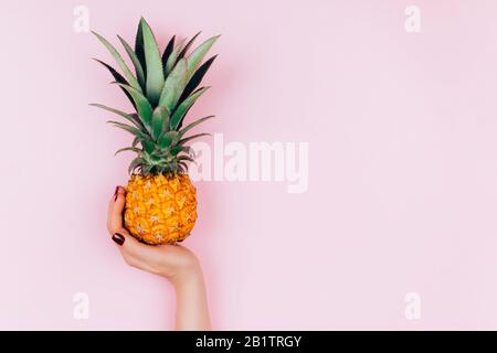 Hands with pineapple on stylish pink background. Stock Photo
