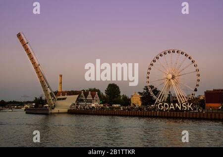 View of Ferris Wheel and lifted Footbridge over Motlawa during sunset. Gdańsk (Danzig in German) is a port city on the Baltic coast of Poland. Stock Photo