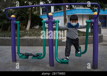 A kid using the walker in a recreational park wearing a surgical mask to prevent the ongoing coronavirus disease. Stock Photo