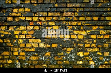 Expired Brickwall with crumbling concrete in black an yellow Stock Photo
