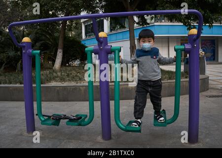 A kid using the walker in a recreational park wearing a surgical mask to prevent the ongoing coronavirus disease. Stock Photo